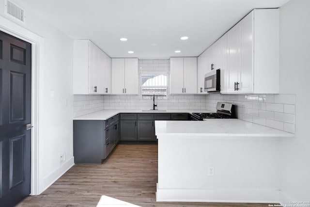 kitchen featuring sink, white cabinetry, appliances with stainless steel finishes, gray cabinets, and kitchen peninsula