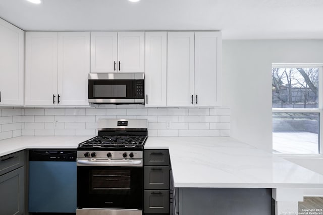 kitchen with gray cabinets, backsplash, stainless steel appliances, light stone countertops, and white cabinets