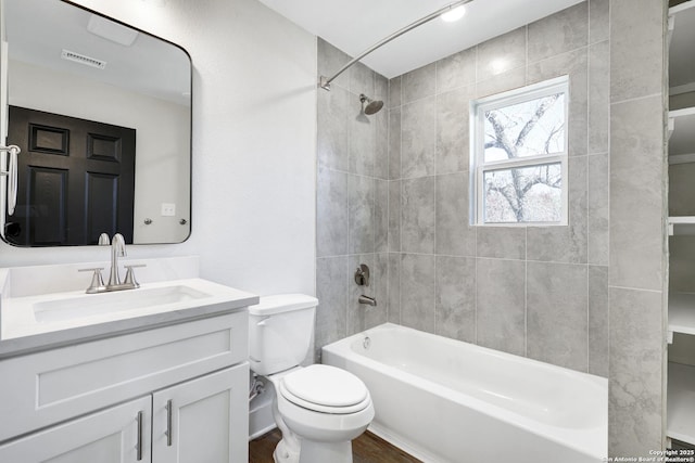 full bathroom featuring tiled shower / bath combo, vanity, hardwood / wood-style floors, and toilet