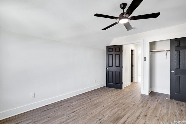 unfurnished bedroom featuring lofted ceiling, light hardwood / wood-style floors, a closet, and ceiling fan