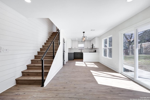 stairs with sink, hardwood / wood-style flooring, and wood walls