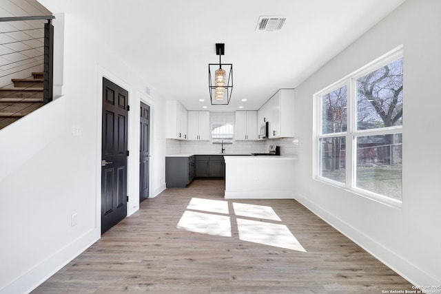 kitchen featuring white cabinetry, hanging light fixtures, gray cabinets, a healthy amount of sunlight, and decorative backsplash