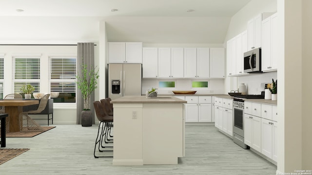 kitchen featuring sink, a kitchen island with sink, stainless steel appliances, white cabinets, and decorative backsplash