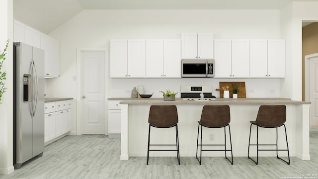 kitchen with a breakfast bar area, stainless steel appliances, an island with sink, white cabinets, and vaulted ceiling