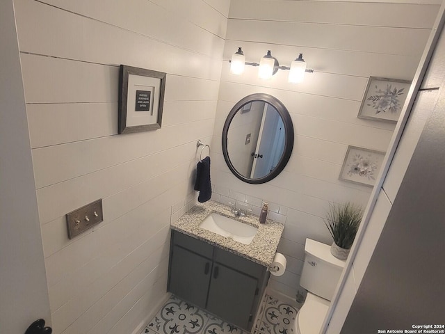 bathroom with vanity, tile walls, and toilet