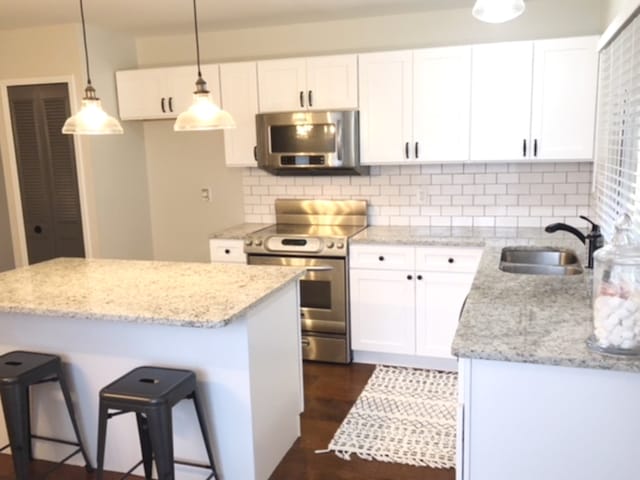 kitchen with pendant lighting, sink, a breakfast bar, white cabinetry, and stainless steel appliances