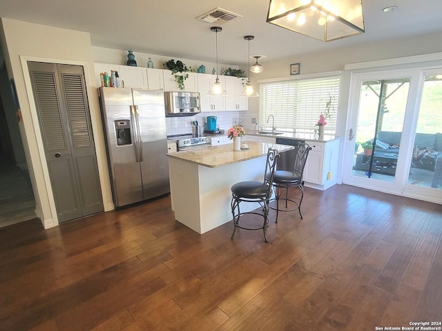 kitchen with a kitchen island, white cabinetry, appliances with stainless steel finishes, and decorative light fixtures