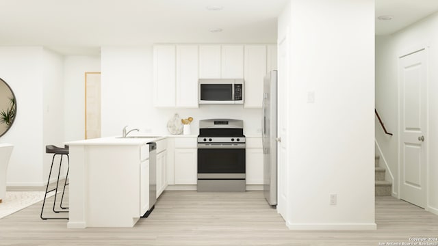 kitchen featuring sink, light wood-type flooring, kitchen peninsula, stainless steel appliances, and white cabinets