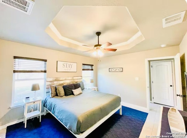 bedroom featuring ceiling fan, a tray ceiling, and multiple windows