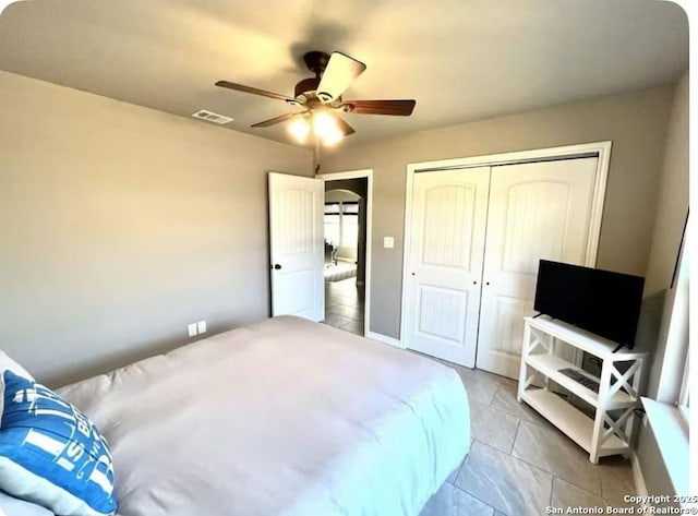 tiled bedroom featuring ceiling fan and a closet