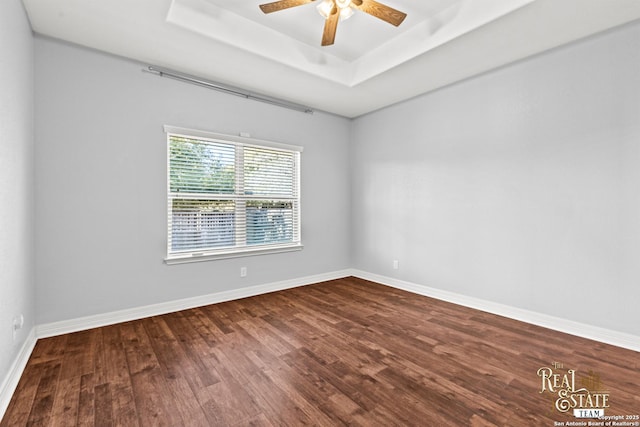 empty room with ceiling fan, a tray ceiling, and hardwood / wood-style floors