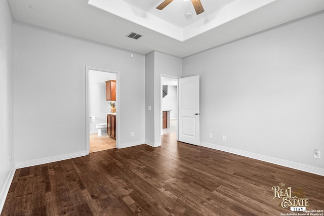 unfurnished bedroom featuring hardwood / wood-style flooring, ensuite bath, a raised ceiling, and ceiling fan