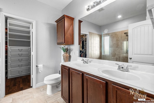 bathroom featuring tiled shower, vanity, and toilet