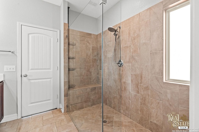 bathroom with a tile shower and vanity