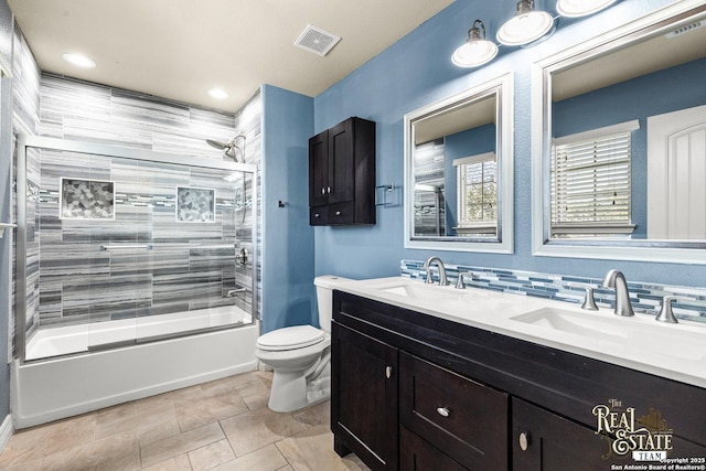 full bathroom with enclosed tub / shower combo, vanity, and toilet