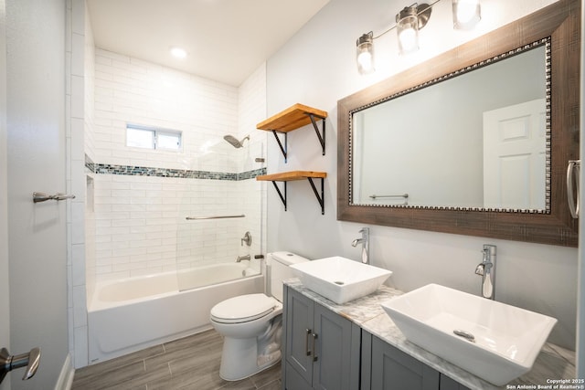 full bathroom featuring tiled shower / bath combo, vanity, and toilet