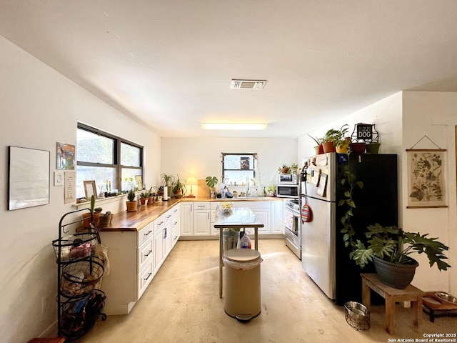 kitchen featuring sink, white cabinetry, butcher block counters, stainless steel appliances, and kitchen peninsula