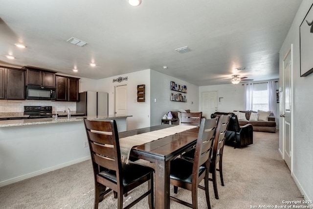 dining room with sink, light carpet, and ceiling fan