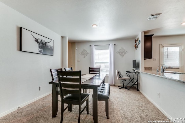 dining area with light carpet, sink, and a healthy amount of sunlight