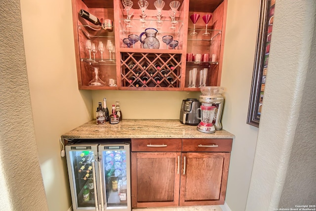 bar featuring light stone countertops and beverage cooler