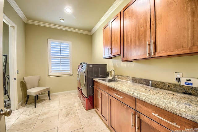 washroom featuring sink, ornamental molding, cabinets, and independent washer and dryer