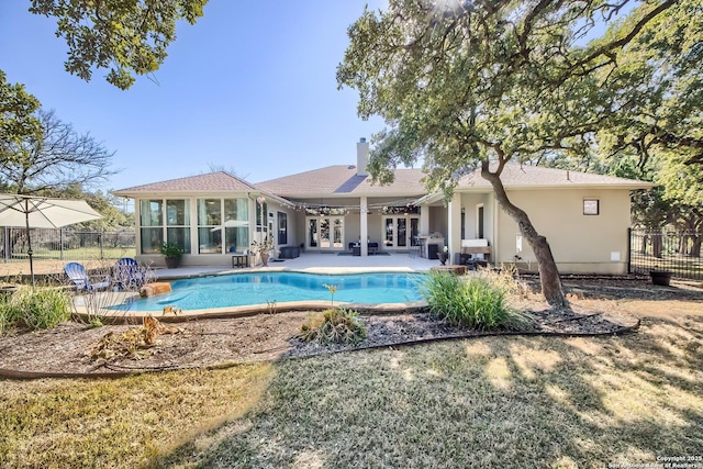 rear view of property with a fenced in pool, a sunroom, and a patio area