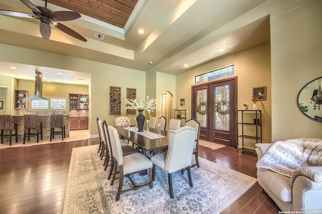 dining room featuring dark hardwood / wood-style flooring, ceiling fan, a raised ceiling, crown molding, and french doors