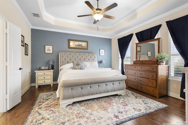 bedroom with crown molding, ceiling fan, dark hardwood / wood-style flooring, and a tray ceiling