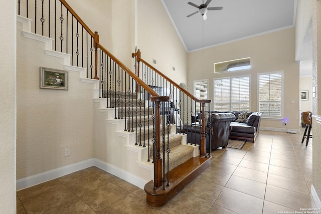 staircase featuring ornamental molding, a towering ceiling, tile patterned floors, and ceiling fan