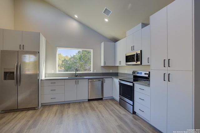 kitchen with sink, appliances with stainless steel finishes, white cabinetry, high vaulted ceiling, and light hardwood / wood-style floors