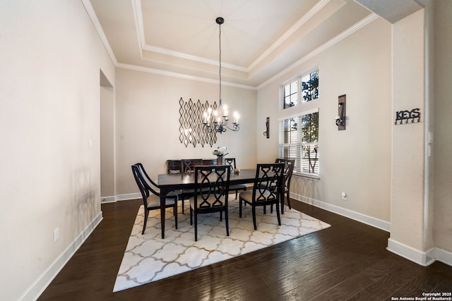 dining space featuring dark hardwood / wood-style floors, ornamental molding, a tray ceiling, and a chandelier