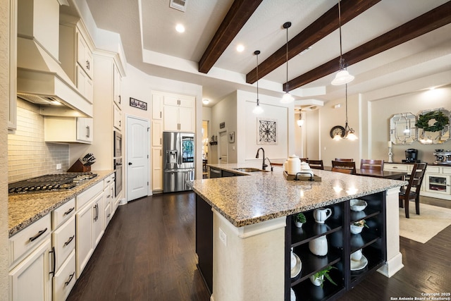 kitchen featuring a spacious island, sink, light stone counters, decorative light fixtures, and appliances with stainless steel finishes