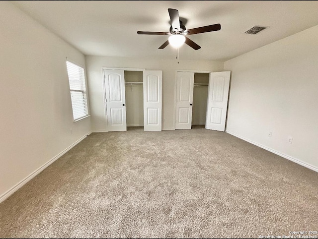 unfurnished bedroom featuring multiple closets, ceiling fan, and carpet