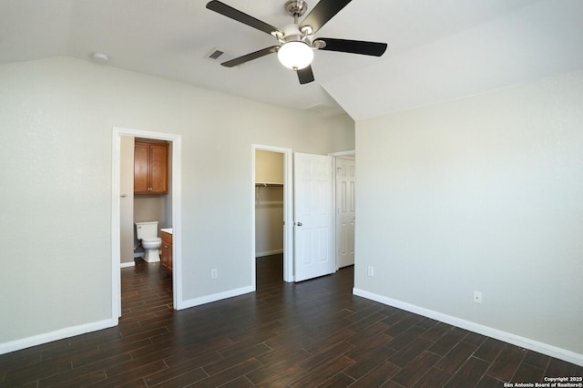 unfurnished bedroom with dark wood-style floors, a walk in closet, visible vents, and baseboards