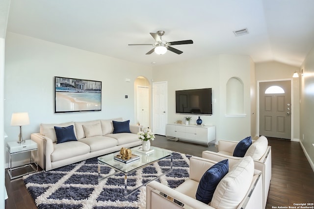 living room featuring arched walkways, dark wood-style flooring, visible vents, a ceiling fan, and vaulted ceiling