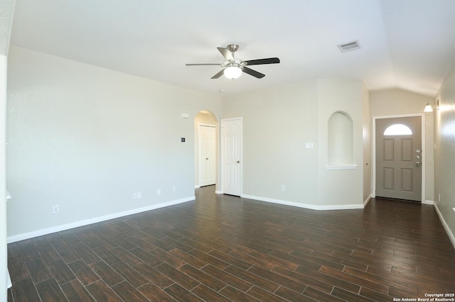 spare room with arched walkways, dark wood finished floors, visible vents, a ceiling fan, and baseboards