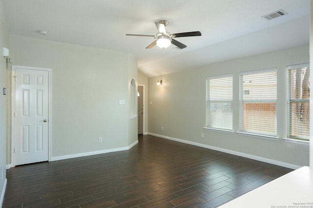 spare room with baseboards, visible vents, arched walkways, and dark wood-type flooring