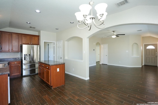 kitchen featuring arched walkways, visible vents, vaulted ceiling, stainless steel fridge with ice dispenser, and dark wood finished floors