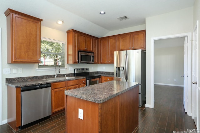 kitchen with wood finish floors, dark countertops, visible vents, appliances with stainless steel finishes, and a sink