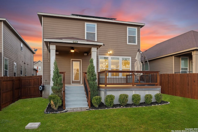 back house at dusk with a wooden deck and a yard