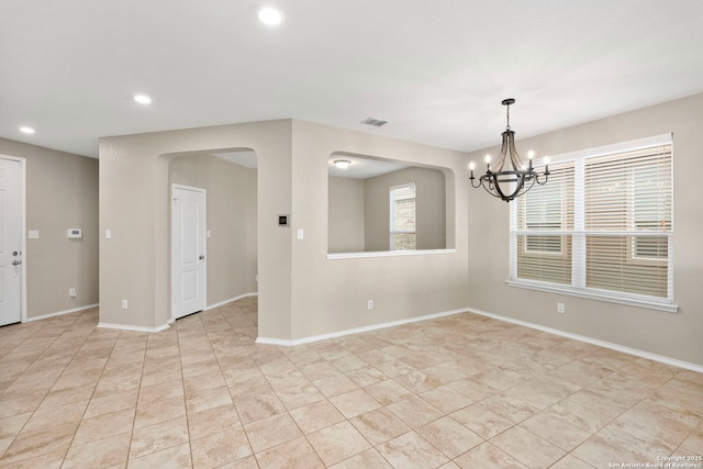 tiled spare room with an inviting chandelier