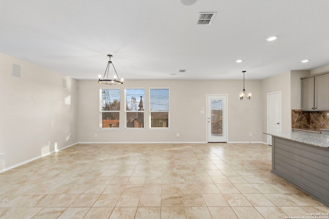 unfurnished living room featuring an inviting chandelier and light tile patterned floors