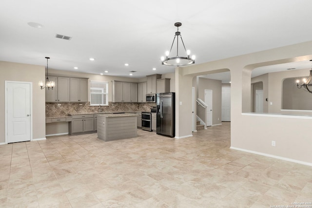 kitchen featuring a chandelier, stainless steel appliances, gray cabinets, and hanging light fixtures