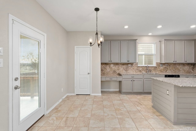 kitchen with light stone counters, decorative light fixtures, gray cabinets, and backsplash