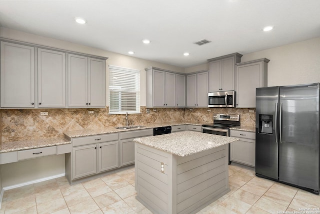 kitchen featuring sink, light stone counters, a kitchen island, stainless steel appliances, and backsplash