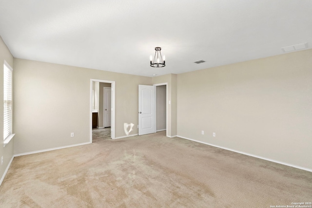 unfurnished room featuring light colored carpet and an inviting chandelier