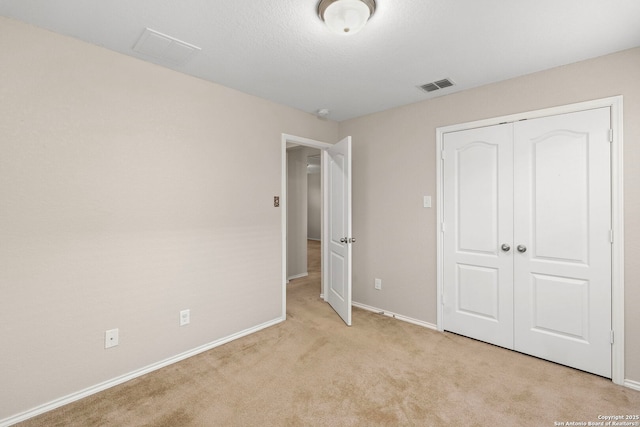 unfurnished bedroom featuring light carpet and a closet