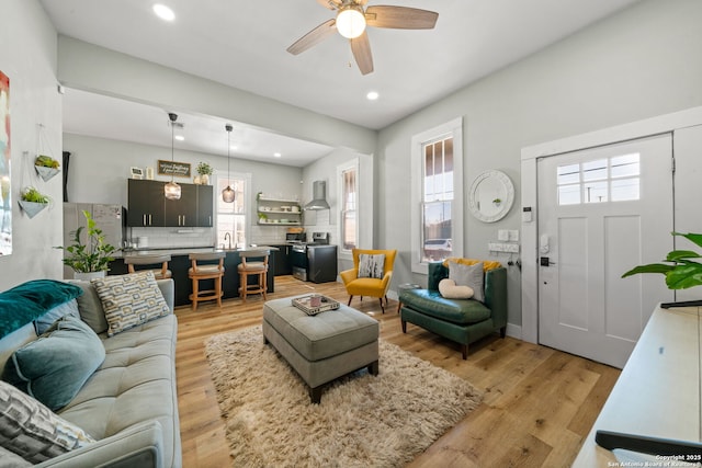 living room with sink, ceiling fan, and light wood-type flooring