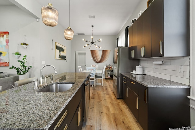 kitchen featuring stone countertops, sink, hanging light fixtures, and light wood-type flooring