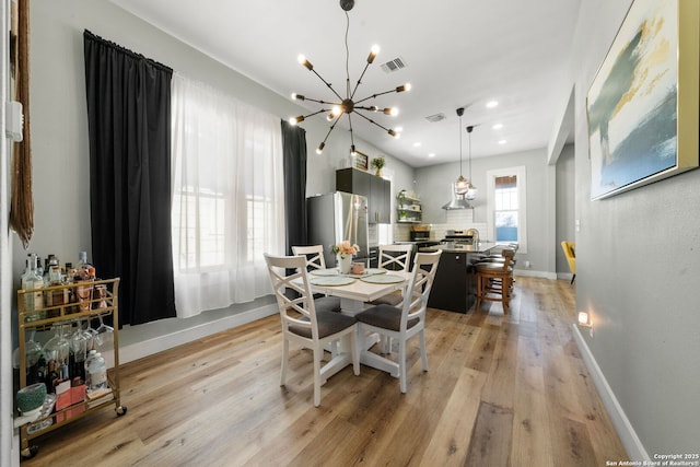 dining space with a notable chandelier and light wood-type flooring